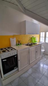 a kitchen with white cabinets and a stove and a sink at Chez Valé in Le Moule +14 photos