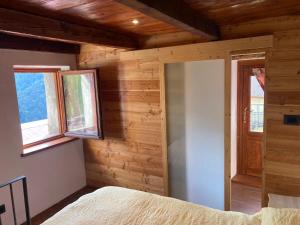 a bedroom with wooden walls and a door and windows at La Casetta Prali in Prali