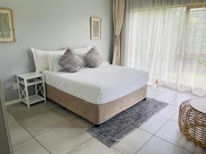 a bedroom with a bed with white sheets and pillows at Villa by The Vaal River in Vanderbijlpark +22 photos