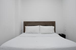 a bed with white sheets and a wooden headboard at Hotel Royal Classy in Villavicencio