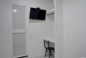 a room with a white wall with a tv and a chair at Hotel Royal Classy in Villavicencio