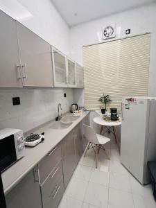a kitchen with a sink and a refrigerator and a table at Modern Apartment 3 in Jeddah