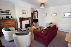 a living room with two chairs and a red couch at Dog Friendly Lakeland Apartment - Private Parking - Central Location in Cockermouth