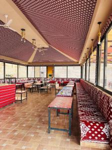 a restaurant with benches and tables in a building at Shaheen Camp Wadi rum in Wadi Rum