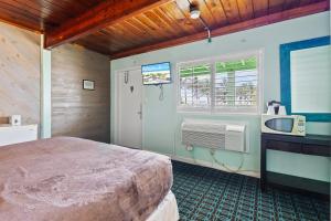 a bedroom with a bed and a tv and a window at Oceanfront Inn Room #9 in Fort Pierce