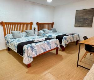 two beds sitting in a room with a table at Hotel Farallon Inn Cancún in Cancún
