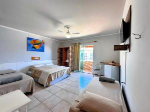 a bedroom with two beds and a flat screen tv at Pousada Convés das Ondas in Penha