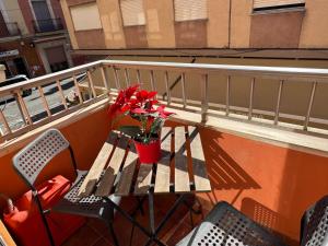 a table and chairs on a balcony with red flowers at Albalat Centro in Albalat de la Ribera