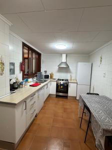 a kitchen with white cabinets and a table and a refrigerator at Albalat Centro in Albalat de la Ribera