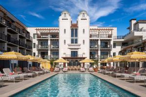 a pool in front of a building with chairs and umbrellas at La Bahia Hotel & Spa in Santa Cruz
