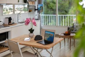 a laptop computer sitting on a wooden table in a kitchen at Tableau de La Ciotat - Host Provence in La Ciotat