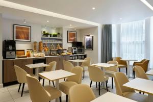 a restaurant with tables and chairs and a kitchen at Four Points Flex by Sheraton London Kensington Olympia in London