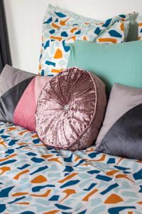 a bed with colorful pillows on it with a bedsheet at Cosy Home proche RER in Noisy-le-Grand