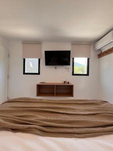 a bedroom with a large bed and a flat screen tv at Boho Suites in Tafí del Valle