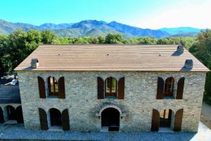 an old brick building with windows and mountains in the background at Chambres de charme in Corte