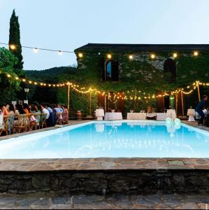 a swimming pool with lights and people sitting at Chambres de charme in Corte