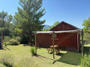 a small wooden cabin with a picnic table in the yard at Cabañas Soledad in Villa Giardino