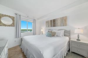 a white bedroom with a large bed and a window at Perdido Skye 64 in Pensacola