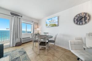 a living room with a table and chairs and a clock at Perdido Skye 64 in Pensacola