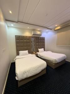 two beds in a room with white sheets at شاليهات وشقق ليالي رهيف in Abha