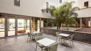 a patio with tables and chairs in front of a building at Sercotel Barcelona El Prat in El Prat de Llobregat