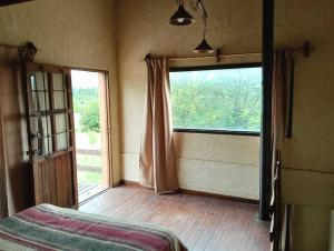 a room with a bed and a large window at Búho Multiespacio in Villa Giardino