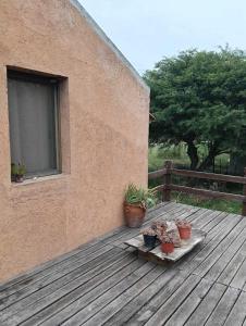 a wooden deck with potted plants and a window at Búho Multiespacio in Villa Giardino