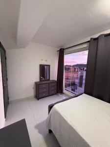 a bedroom with a bed and a tv and a window at Moon Apartamentos C1 in San Cristóbal