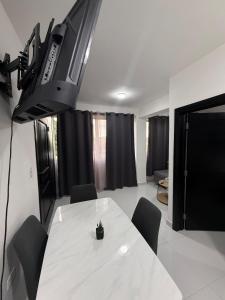 a room with a white table with chairs and a tv at Moon Apartamentos C1 in San Cristóbal