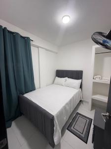 a small bedroom with a bed with green curtains at Moon Apartamentos C1 in San Cristóbal +3 photos