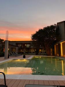 a swimming pool in front of a building with a sunset at Rockaway Apart in Miramar