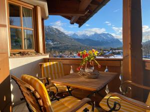 a table and chairs on a balcony with a view of mountains at Apartment Sonnenhang in Wallgau