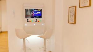 two white chairs in a room with a tv on a wall at Apartamento moderno en el centro de Tavernes in Tavernes de Valldigna