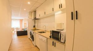 a kitchen with white cabinets and a microwave at Apartamento moderno en el centro de Tavernes in Tavernes de Valldigna +1 photo