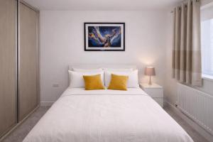 a bedroom with a large white bed with yellow pillows at Ebbsfleet Luxe in Swanscombe