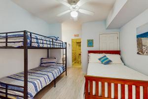 a bedroom with two bunk beds and a ceiling fan at SB50 Saltwater Sanctuary in Sunset Beach