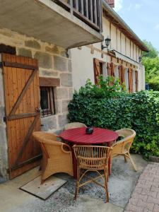 a red table with two chairs and a wooden door at Les colombages bis in Pazayac +21 photos