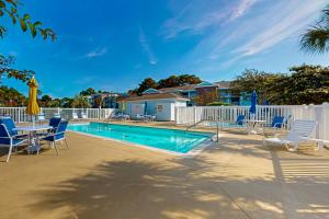 a swimming pool with chairs and a table and a fence at SB72 Sea Trail Golf-Beach Condo in Sunset Beach