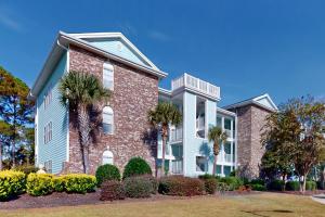 a large brick house with palm trees and bushes at SB72 Sea Trail Golf-Beach Condo in Sunset Beach