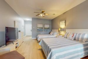 a bedroom with two beds and a flat screen tv at SB72 Sea Trail Golf-Beach Condo in Sunset Beach +20 photos