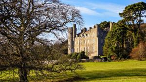 a castle sitting on top of a lush green field at Oaktree Manor - BBQ, games rooms and pet friendly in Castlewellan