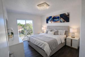 a white bedroom with a bed and a balcony at Villa Miami Lakes 2 in Hialeah