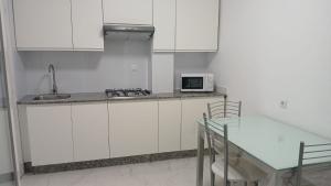 a kitchen with white cabinets and a table and a microwave at Enseñanza in Ourense