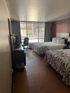 a hotel room with two beds and a desk with a television at Lubbock Regency Inn in Lubbock