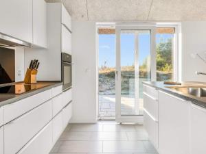 a kitchen with white cabinets and a sliding glass door at 5 star holiday home in Rømø in Toftum