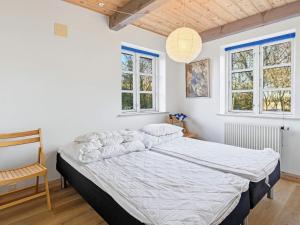 a bedroom with a bed and a chair and windows at 5 star holiday home in Gram in Gram