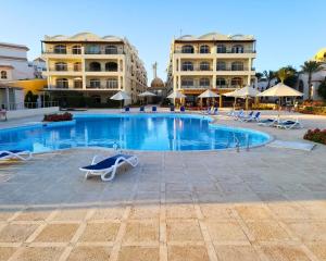 a swimming pool with chairs and buildings in the background at Beachfront luxury Palm Beach Piazza Private Beach in Hurghada