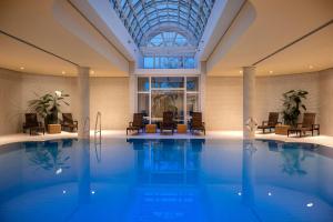a swimming pool with chairs and a table in a building at Leonardo Hotel Weimar in Weimar