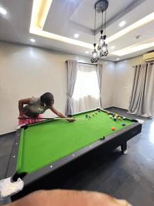 a woman playing pool on a green pool table at Shortlet247 in Hausa