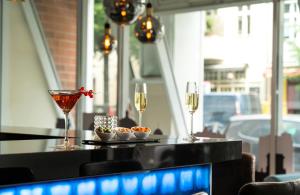 a bar with two glasses of wine and some snacks at Leonardo Hotel Berlin in Berlin +12 photos